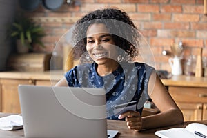 Smiling biracial female make payment on laptop online