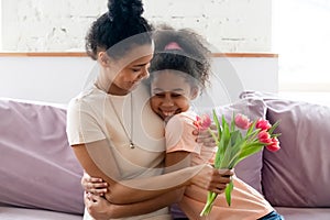 Smiling biracial mom and daughter hug celebrating holiday together