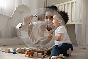 Smiling biracial mother playing with little baby