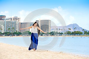 Smiling biracial teen girl walking along beach in Honolulu, Hawaii