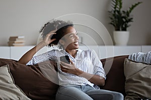 Smiling biracial woman relax on sofa using cellphone