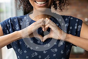 Smiling biracial woman show heart hand gesture