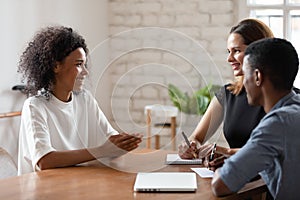 Smiling biracial woman talk with employers at job interview
