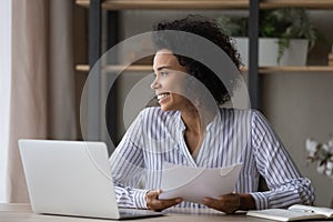 Smiling biracial woman work on laptop look in distance