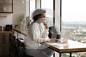 Smiling biracial woman work on laptop thinking