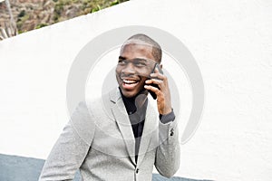 Smiling black businessman talking with phone outside