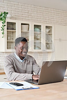 Smiling black businessman working remotely from homeoffice on laptop computer. photo