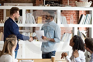 Smiling black CEO handshake Caucasian employee greeting with ach