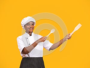 Smiling Black Chef Woman Pointing At Copy Space With Spatulas