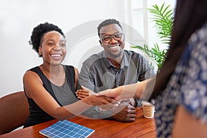 Smiling Black couple shake hands with financial advisor, lawyer at meeting