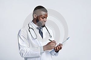 Smiling black doctor with stethoscope collecting patient anamnesis