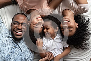 Smiling black family relaxing on bed with closed eyes.