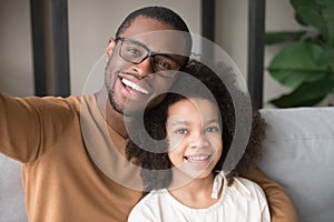 Smiling black father and child taking selfie looking at camera