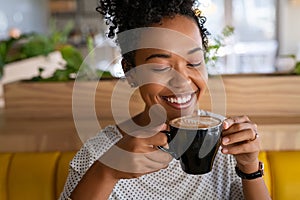 Smiling black girl drinking cappuccino at cafeteria