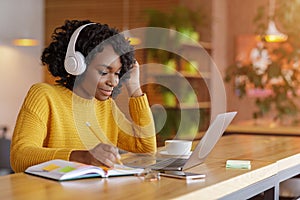 Smiling black girl with headset studying online, using laptop