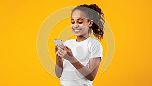 Smiling black girl using mobile phone at studio