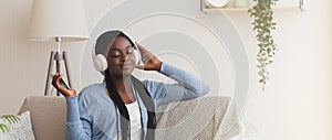 Smiling Black Girl Wearing Wireless Headphones, Enjoying Listening Music From Smartphone