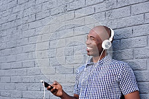 Smiling black guy with headphones and mobile phone