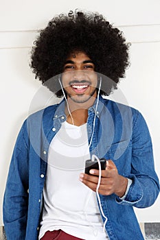 Smiling black guy listening to music on smart phone