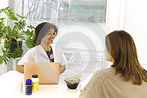 Smiling black lady doctor chatting with female patient at clinic advicing her vitamins photo