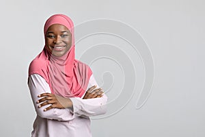 Smiling black lady in hijab posing on grey