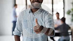 Smiling black male employee demonstrating thumb up gesture recommending partnership