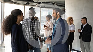 Smiling black male manager talk to clients at office space