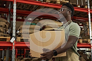 Smiling Black Man Carrying Boxes in Warehouse