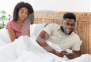 Smiling black man chatting with lover while wife watching him