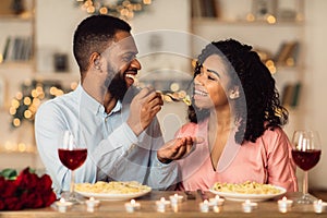 Smiling black man feeding his happy woman with pasta