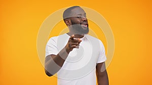 Smiling black man pointing finger, winking knowingly against yellow background
