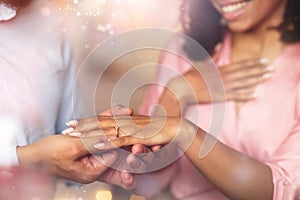 Smiling black man putting wedding ring on his woman finger