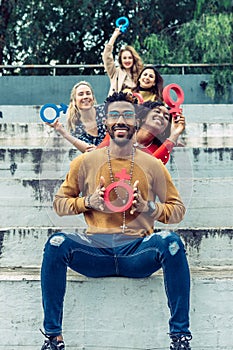 a smiling black man shows an upside-down feminist symbol to the camera as if it were a catholic cross