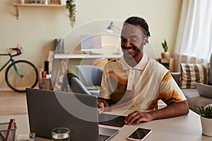 Smiling black man using pen tablet at home office