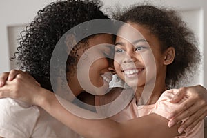 Smiling black mother and daughter embrace cuddle together