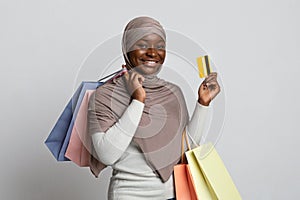Smiling Black Muslim Woman In Hijab Holding Shopping Bags And Credit Card