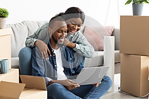 Smiling Black Spouses Ordering Decorations For Their New Flat Online With Laptop
