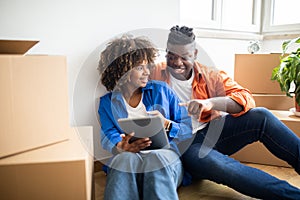 Smiling Black Spouses Using Digital Tablet While Relocating To New Apartment