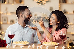 Smiling black woman feeding her man on a date