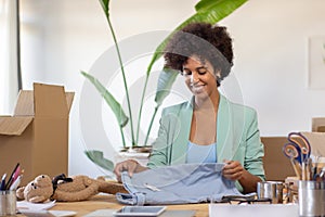 Smiling black woman folding clothes for dispatch