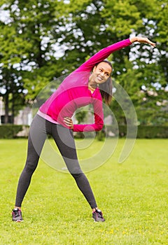 Smiling black woman stretching leg outdoors