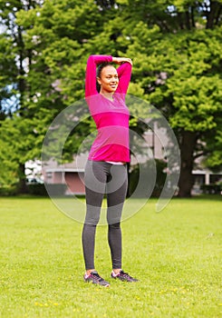 Smiling black woman stretching leg outdoors