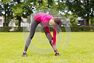 Smiling black woman stretching leg outdoors