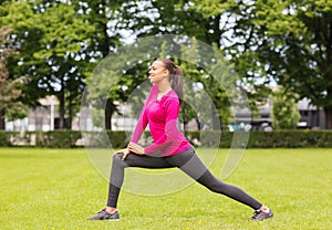 Smiling black woman stretching leg outdoors