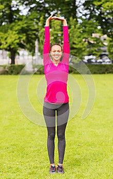 Smiling black woman stretching leg outdoors