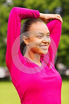 Smiling black woman stretching leg outdoors