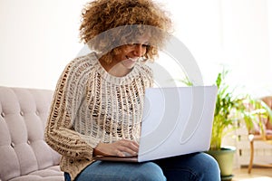 Smiling black woman using laptop computer at home