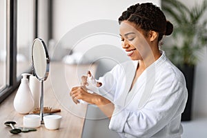 Smiling Black Woman Using Moisturising Cream For Hands At Home