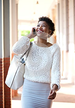 Smiling black woman walking and talking with cell phone