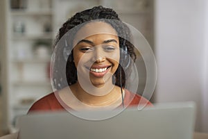 Smiling Black Woman Wearing Headset Using Laptop Indoors